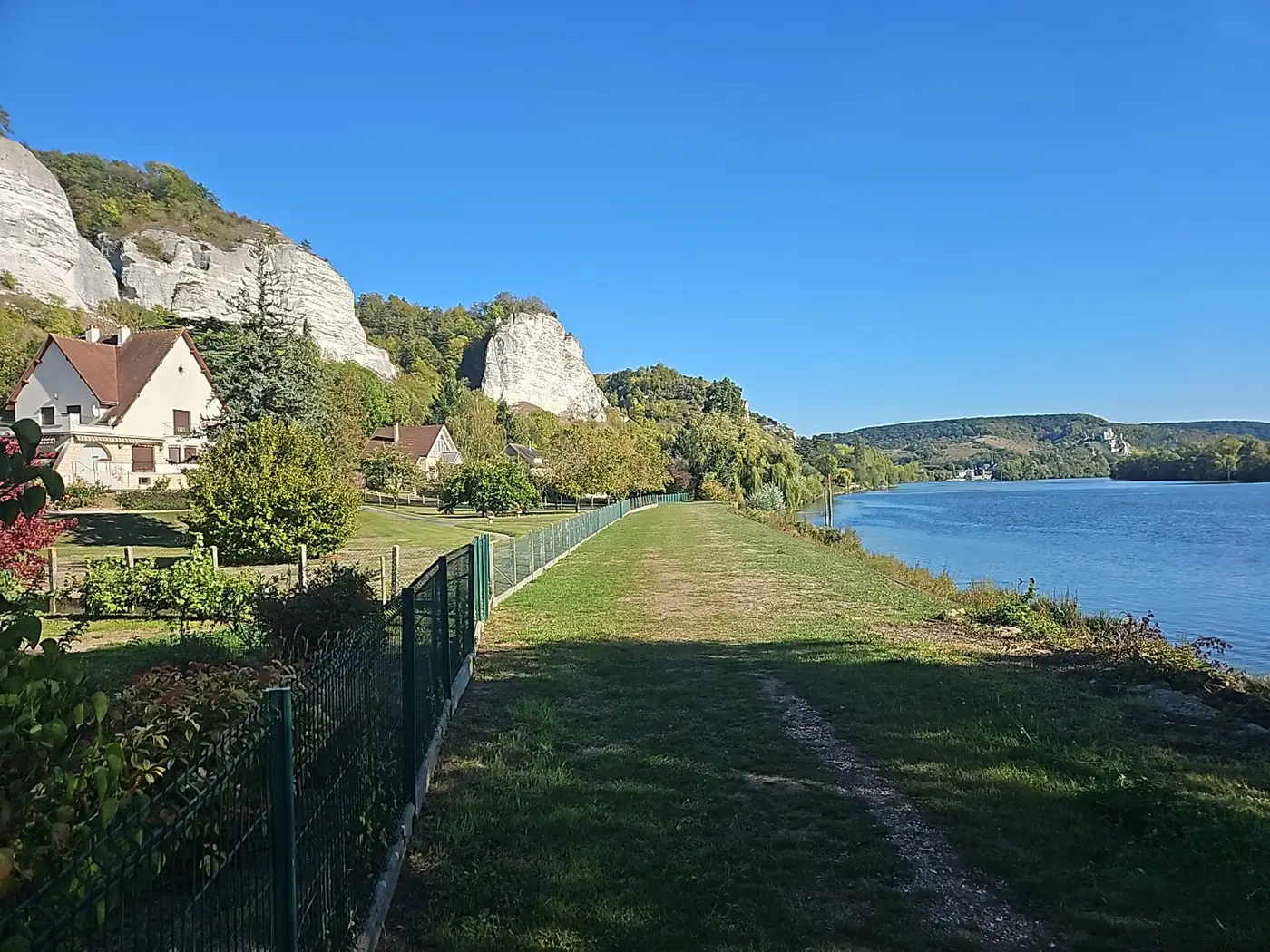 Grassy riverside path beside the Seine with the cliffs of Les Andelys